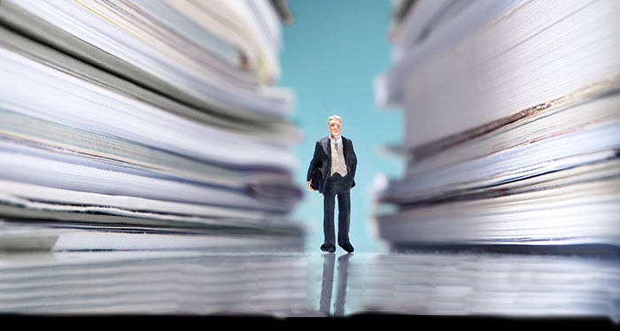 small figure walking among books the size of buildings